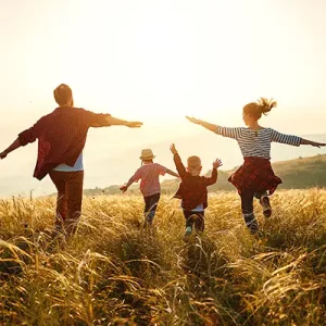 Ein Bild mit einer glücklichen Familie, die auf die untergehende Sonne zurennt.